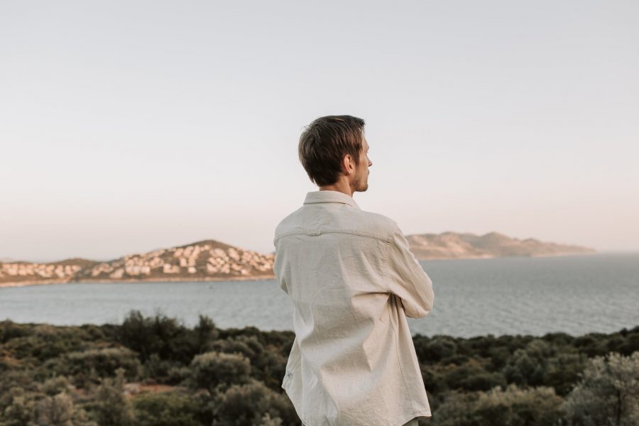 man in white long sleeve shirt looking at the sea