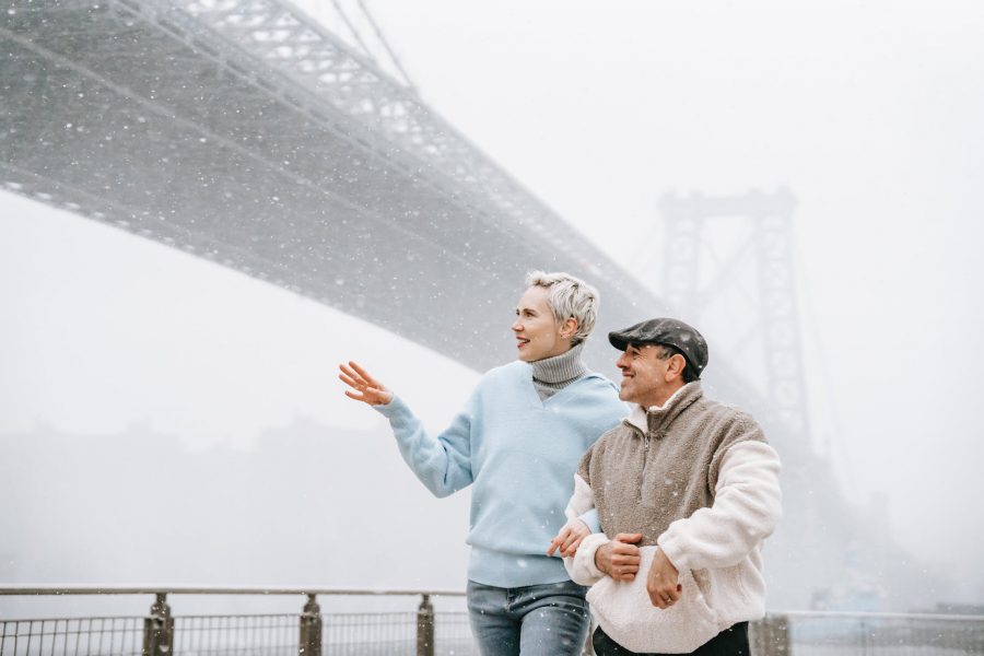 smiling couple walking on embankment in winter day