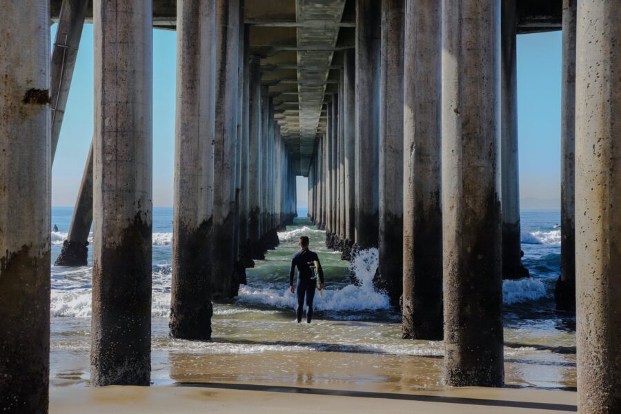 Mjesečni horoskop za rujan, surfer walking toward waves under bridge